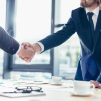 two men shaking hands over an agreement to hire a business consultant