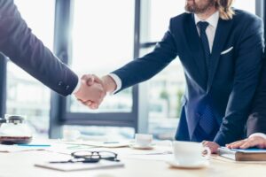 two men shaking hands over an agreement to hire a business consultant