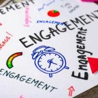 Sheet of paper with written words ENGAGEMENT on table, closeup improve social media engagement