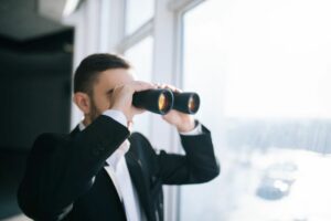 Businessman with low engagement on his social media binoculars spying on competitors.